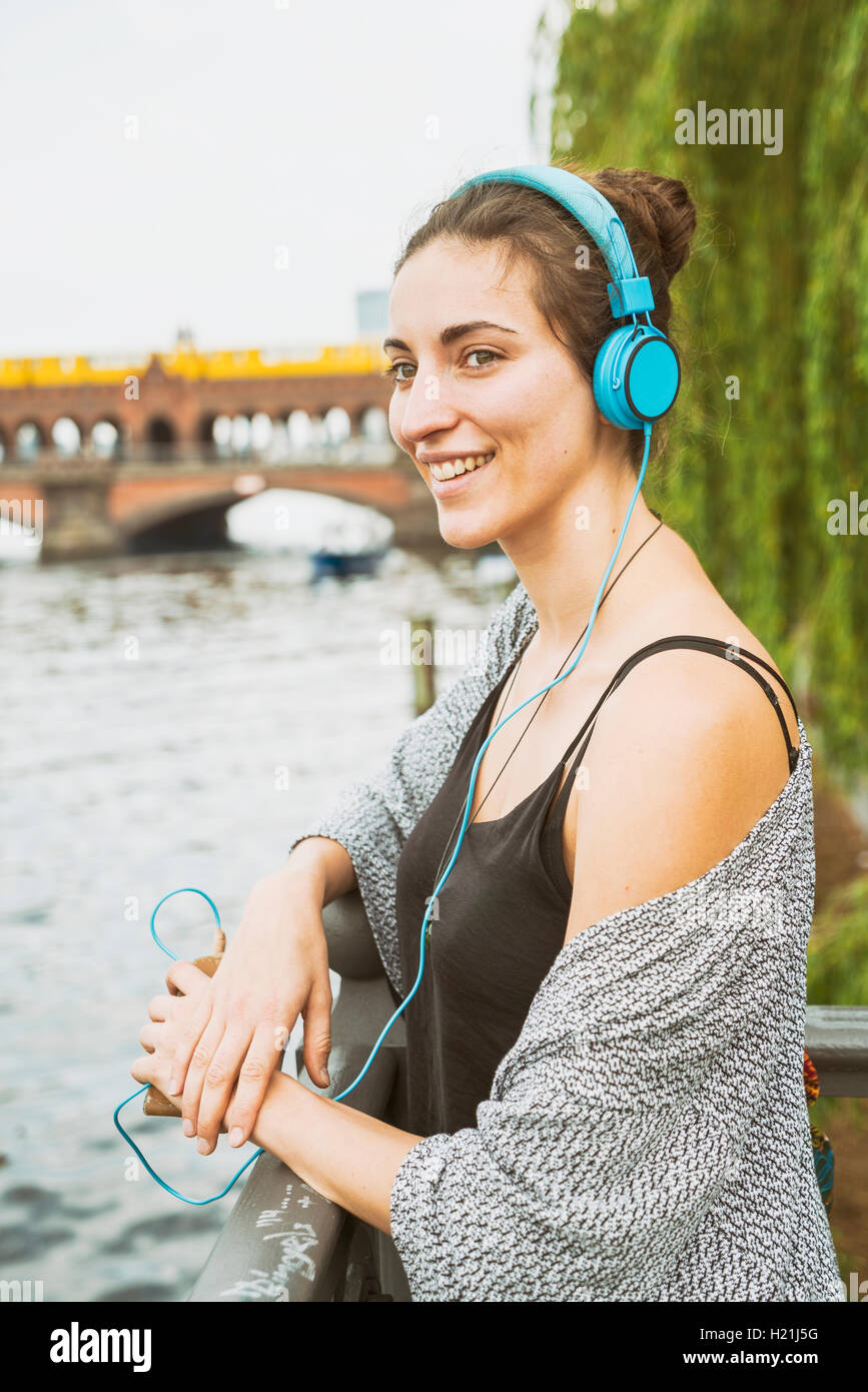 Allemagne, Berlin, relaxed woman listening music with headphones Banque D'Images