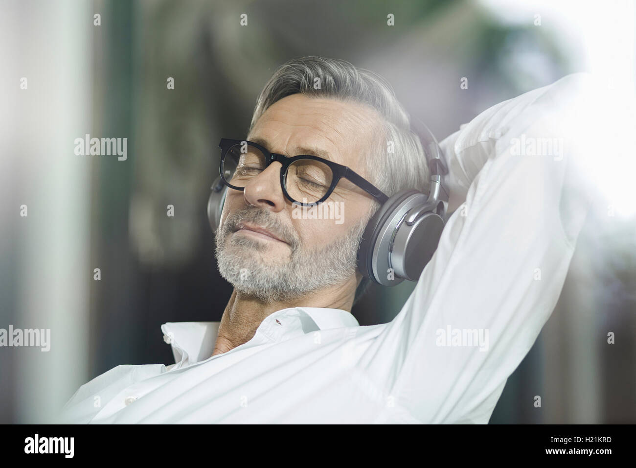 Portrait d'un homme avec les yeux fermés écoutant de la musique avec des écouteurs Banque D'Images