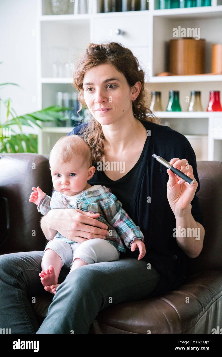 Woman smoking cigarette électronique à côté d'un bébé. Banque D'Images