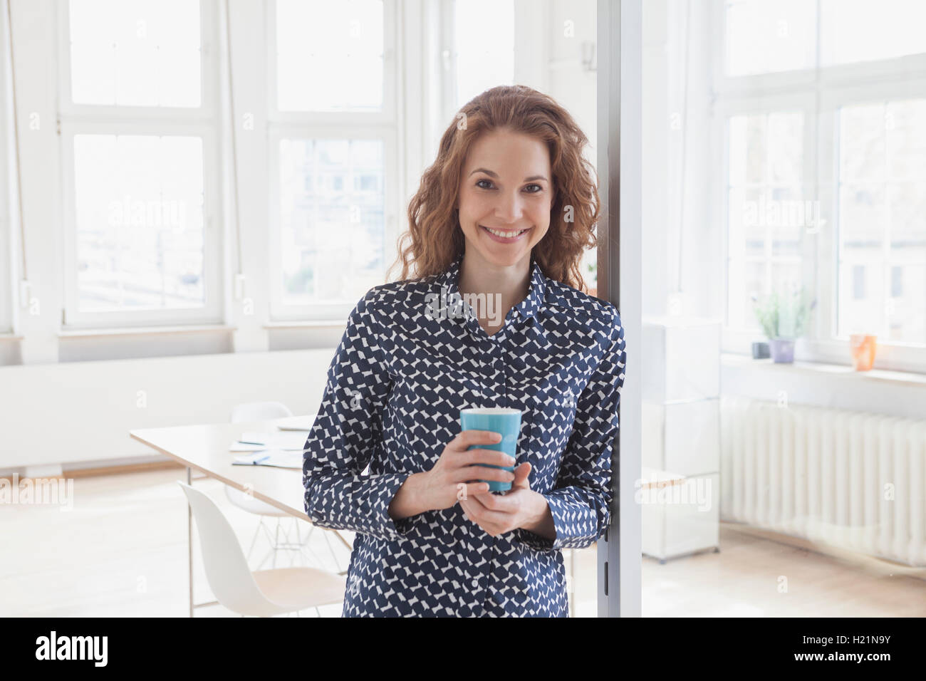 Portrait of smiling woman holding cup in office Banque D'Images
