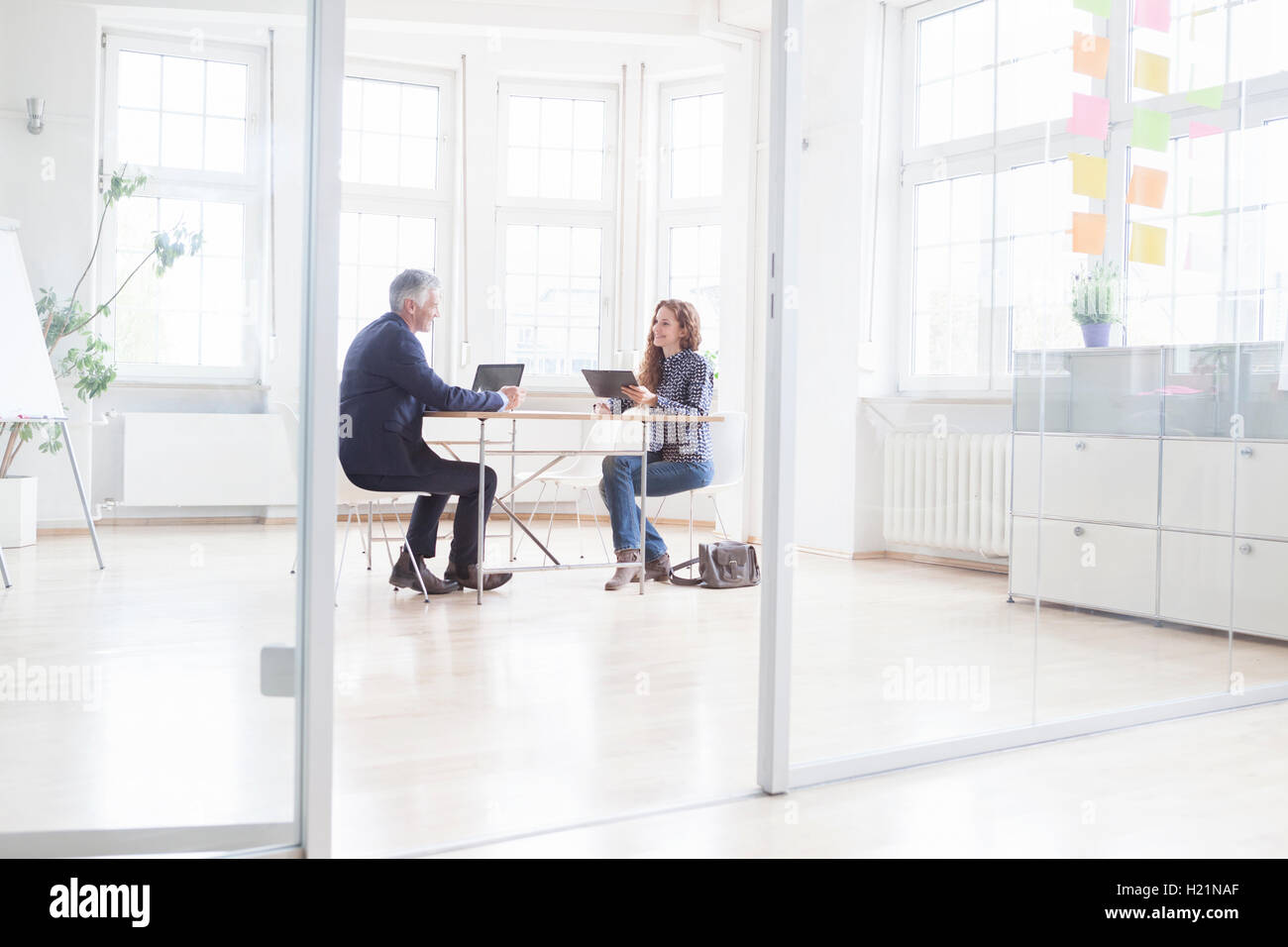 Businessman and woman with laptop and tablet in bright office Banque D'Images