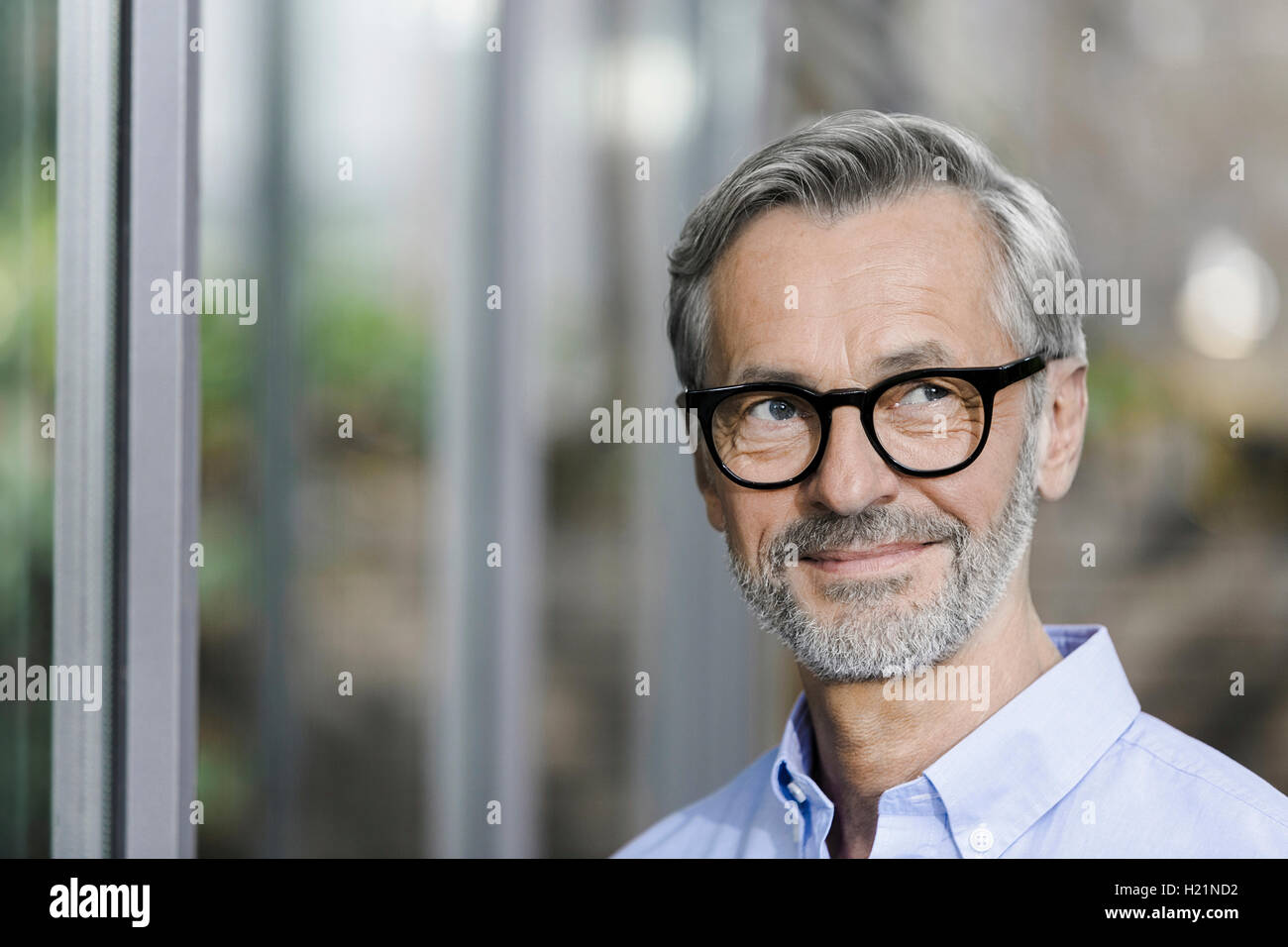 Portrait of smiling man avec barbe et cheveux gris portant des lunettes Banque D'Images