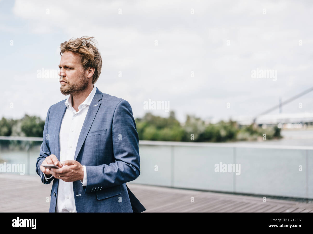 Businessman standing on bridge holding cell phone Banque D'Images