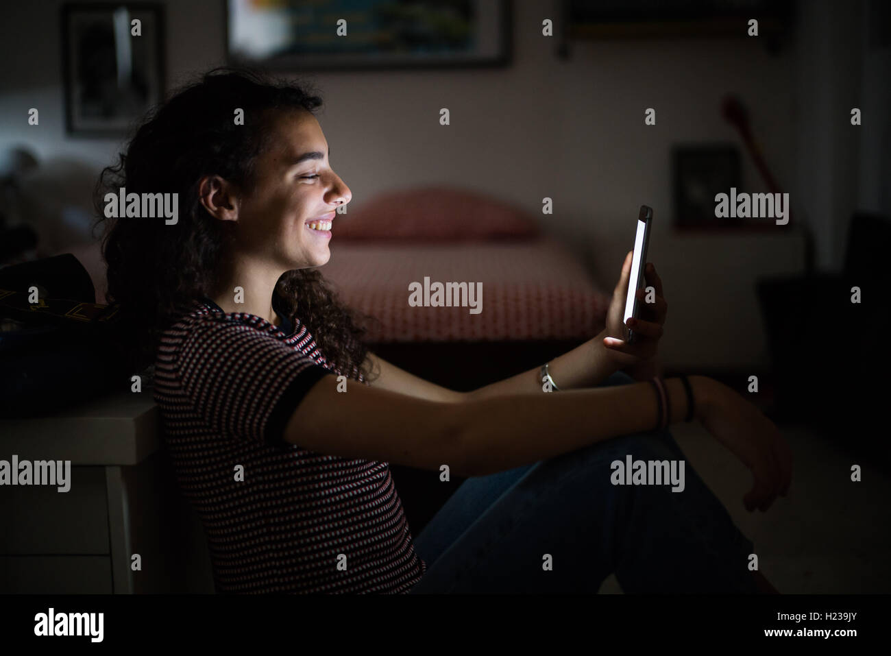 Adolescente en utilisant un smartphone dans la nuit. Banque D'Images