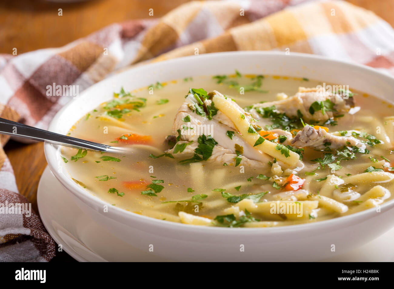 Soupe poulet et nouilles en bol blanc avec cuillère Banque D'Images