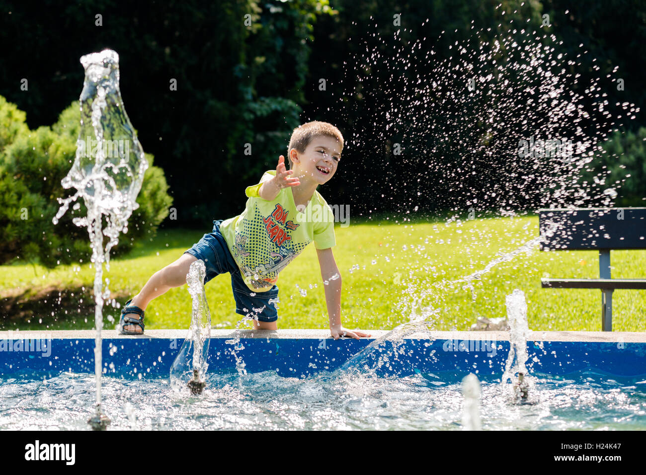 Beau garçon faisant des éclaboussures dans la fontaine Banque D'Images