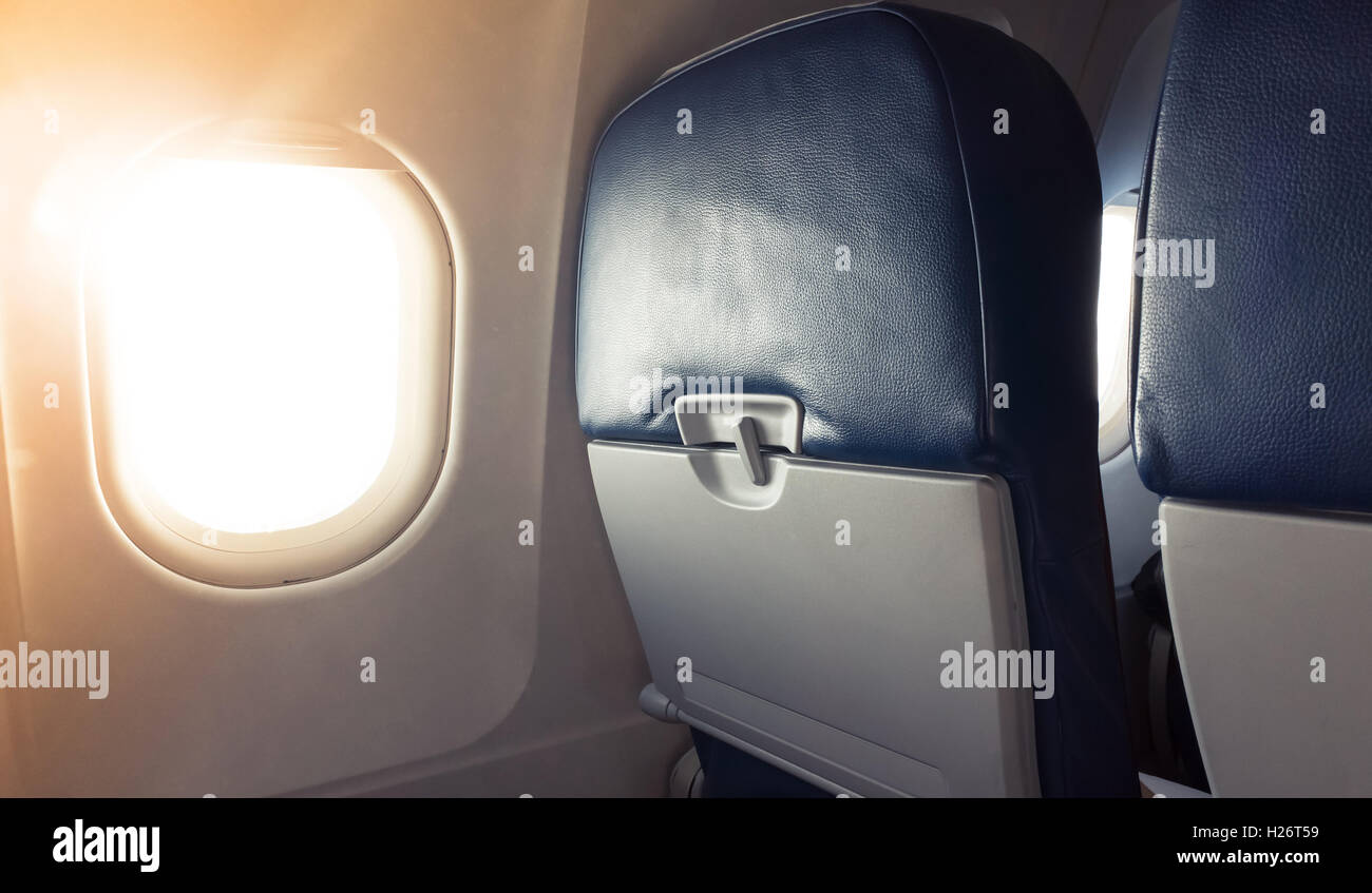 Fragment intérieur d'avion de passagers. Cabine Principale chaises avec table pliante et Hublot lumineux avec lumière naturelle du lens flare Banque D'Images
