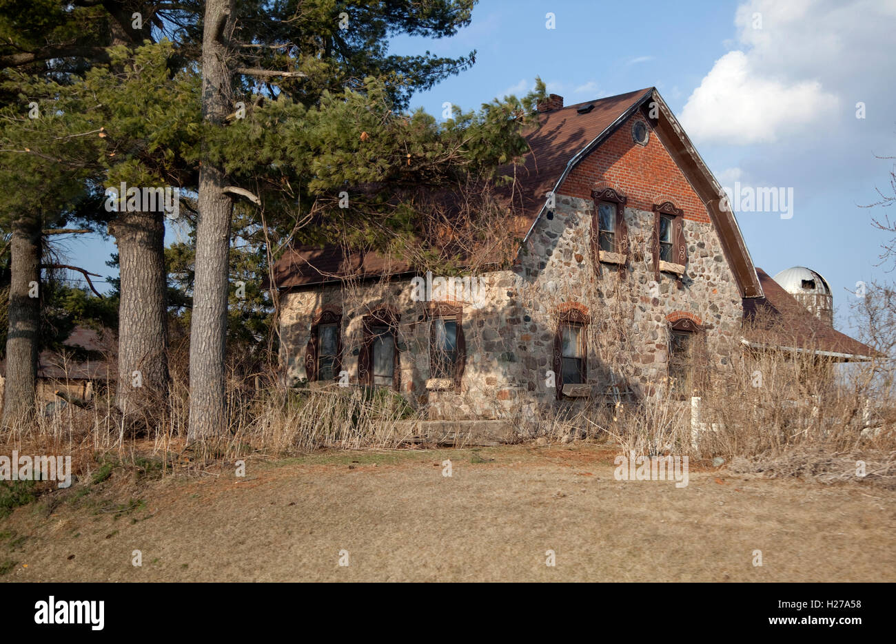 Split classique maison de deux étages en pierre situé sur une ferme près d'une touffe d'arbres verts. La route 63 Wisconsin WI USA Banque D'Images