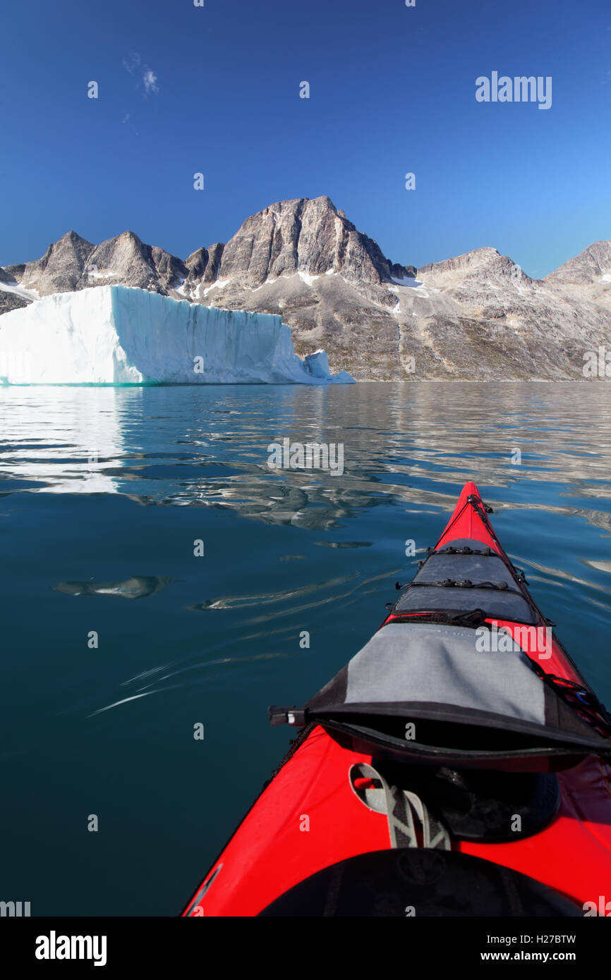 Kayakiste de mer Ikaasatsivaq la pagaie sur la montagne ci-dessous Fjord et iceberg tabulaire, l'île d'Ammassalik, Est du Groenland Banque D'Images