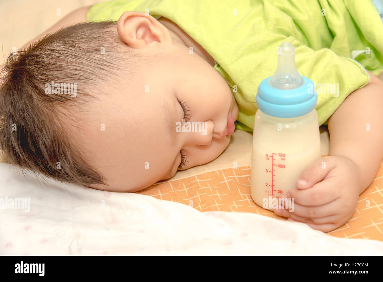 Sommeil Bébé asiatique dans sa main holding baby bouteille de lait Banque D'Images