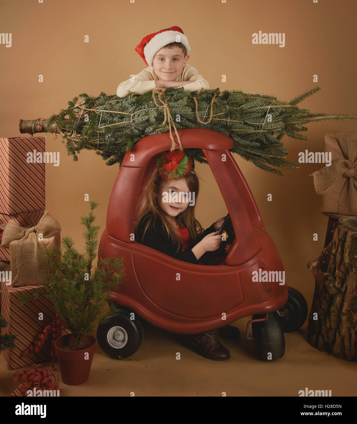 Deux enfants jouent à Noël dans un contexte de studio avec un arbre et des cadeaux pour une maison de vacances ou de décoration concept. Banque D'Images