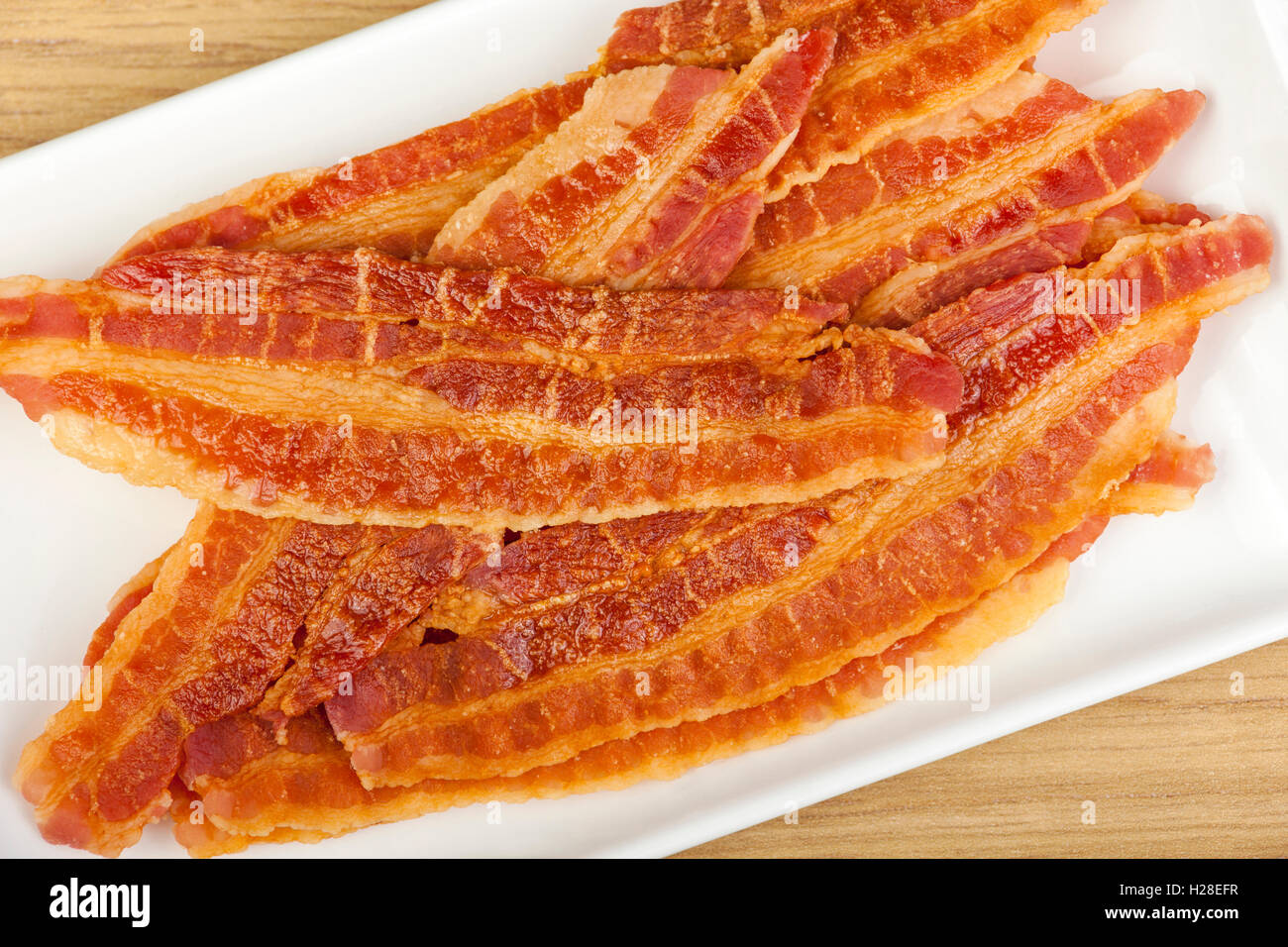 Tranches de bacon croustillant frit frais préparés sur une assiette rectangulaire blanche Banque D'Images