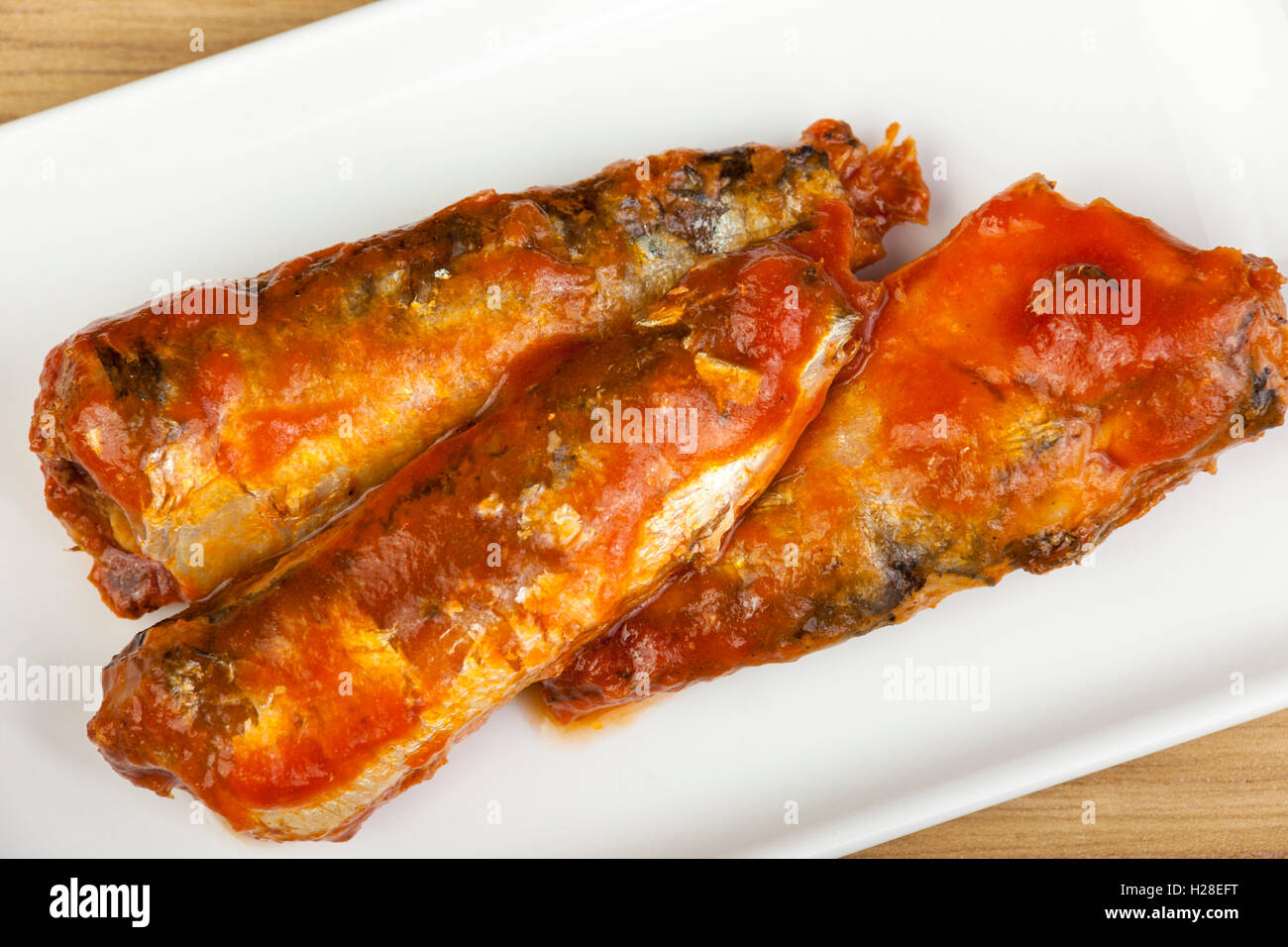 Sardines dans une riche sauce tomate sur une assiette rectangulaire blanche Banque D'Images