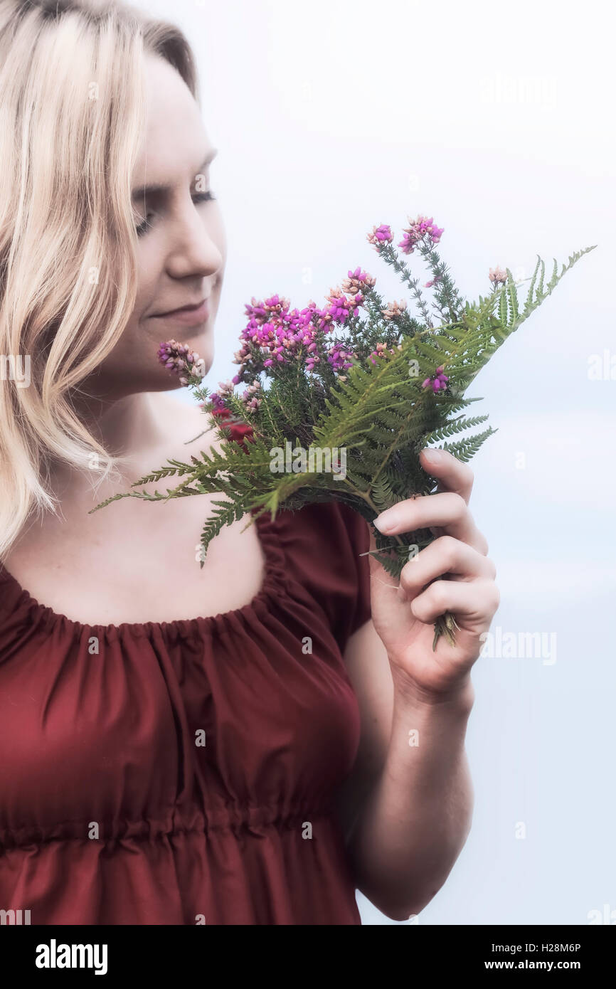 Portrait d'une femme blonde avec un bouquet de fleurs de bruyère Banque D'Images