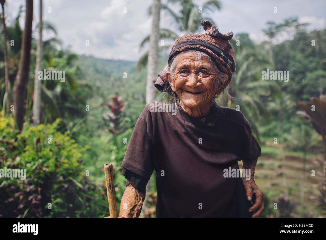 Portrait of senior woman avec une canne dans le village. Jeune femme souriante à l'extérieur dans la campagne. Banque D'Images