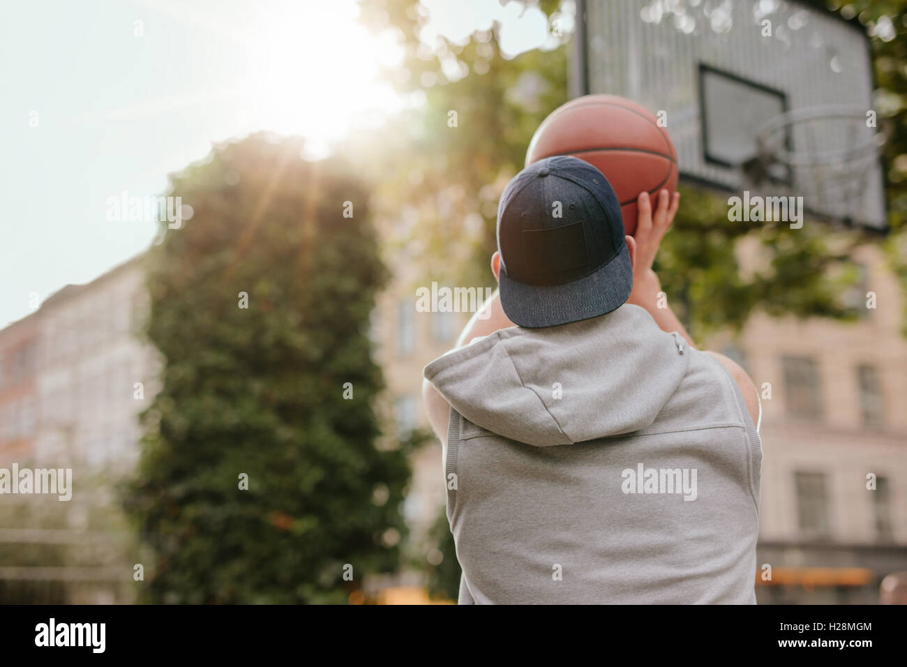 Vue arrière Vue d'un joueur de basket-ball streetball pousses. Jeune homme jouant au basket-ball sur une cour sur une journée d'été. Banque D'Images