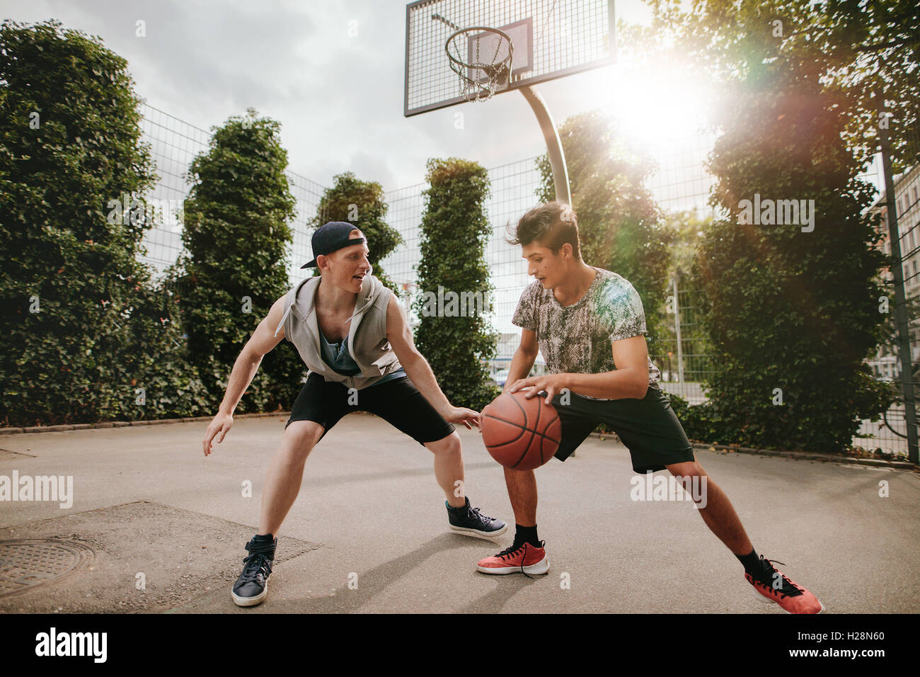 Amis adolescents jouer streetball les uns contre les autres et s'amuser. Deux jeunes hommes ayant un match de basket-ball extérieur sur cour Banque D'Images