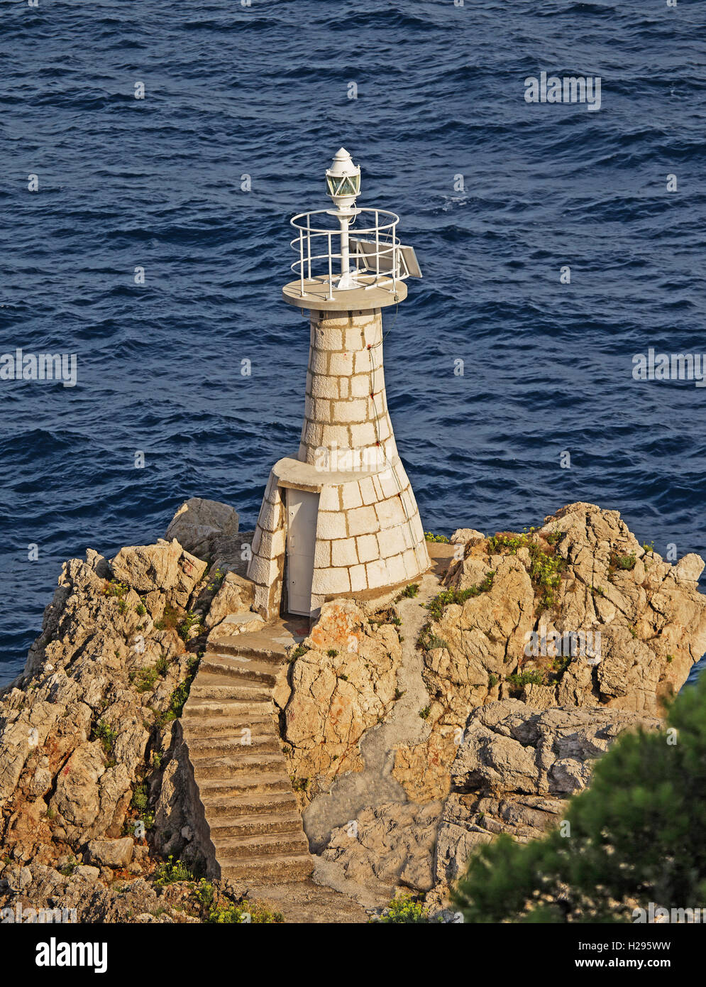 Un phare perché sur les rochers au bas d'une falaise Banque D'Images