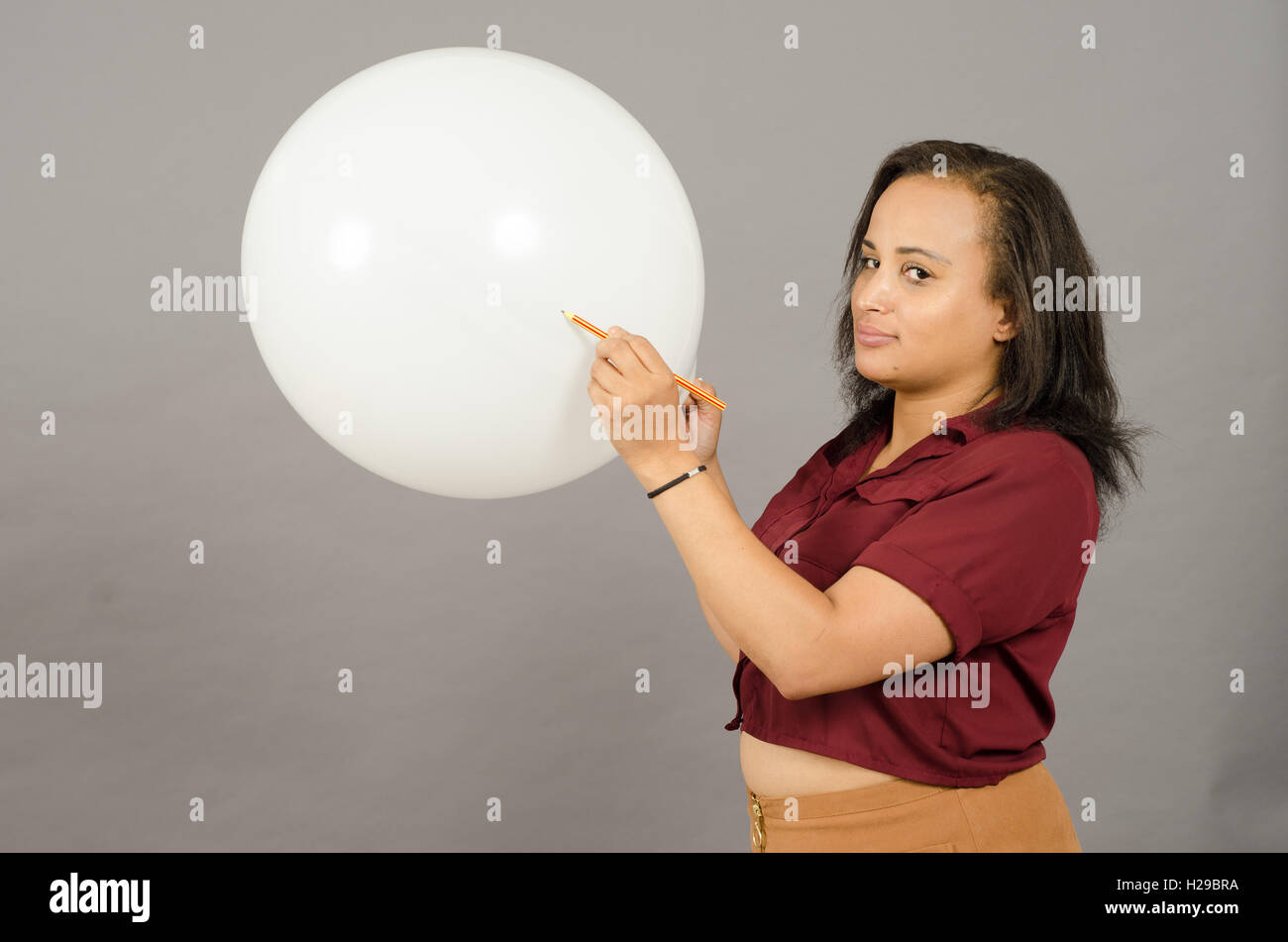 Femme adulte débordant un grand ballon blanc avec un crayon. Banque D'Images