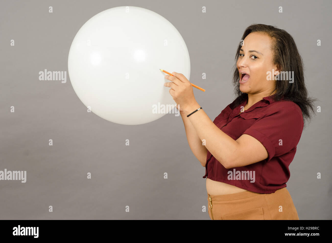 Femme adulte débordant un grand ballon blanc avec un crayon. Banque D'Images