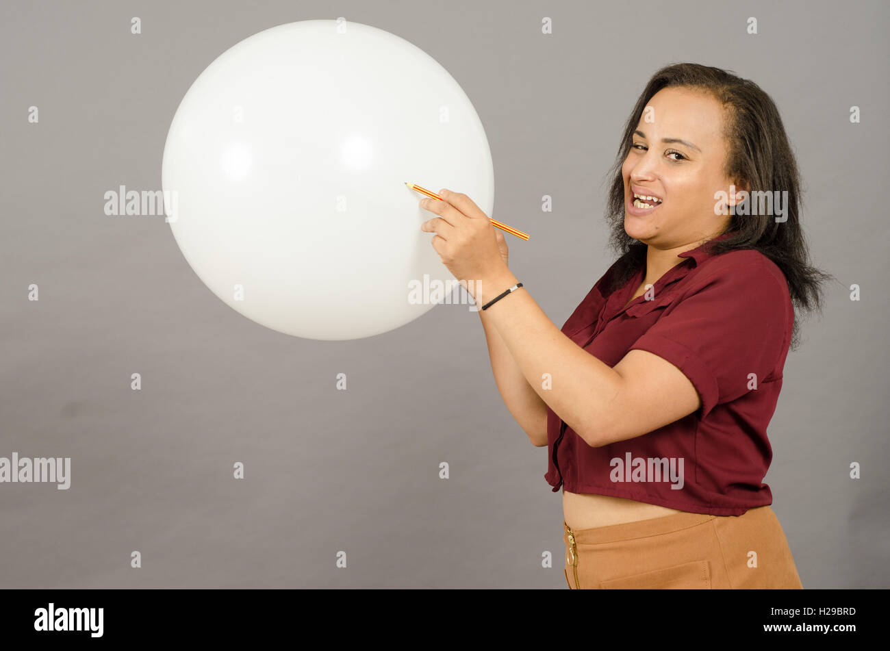 Femme adulte débordant un grand ballon blanc avec un crayon. Banque D'Images