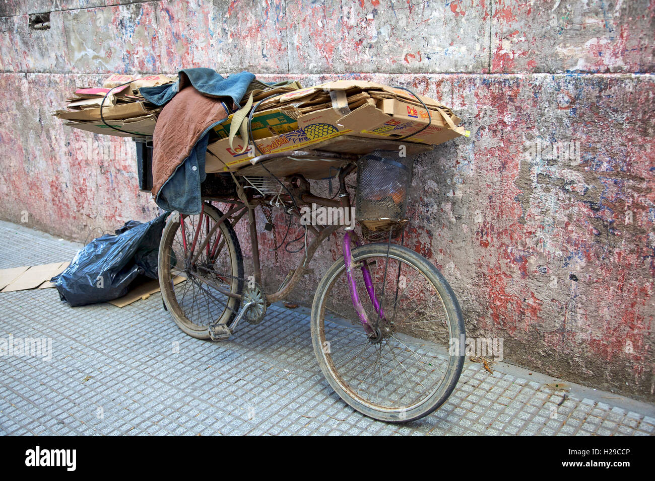 Vieux vélo stationné le long mur sale avec du carton Banque D'Images
