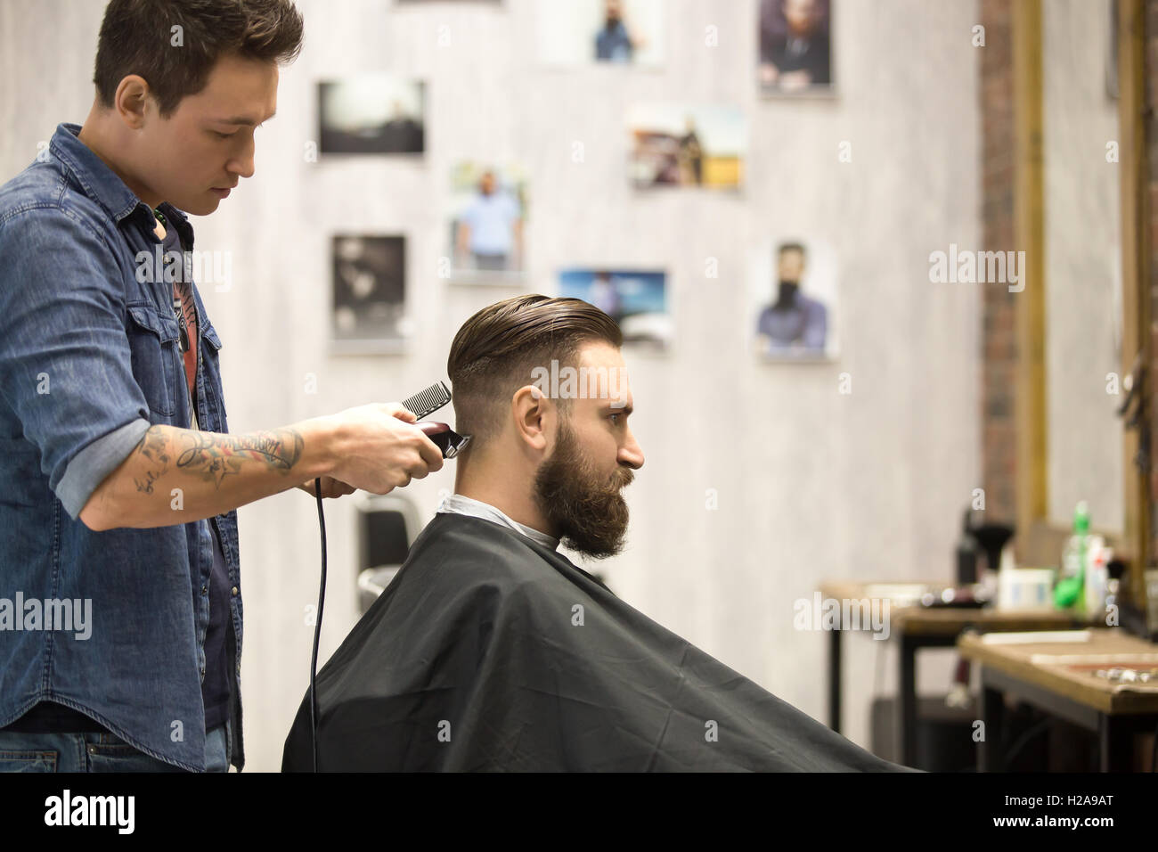 Vue de côté portrait of handsome young bearded caucasian man se coupe de la mode moderne dans un salon de barbier. Cool hommes Instituts de wi Banque D'Images