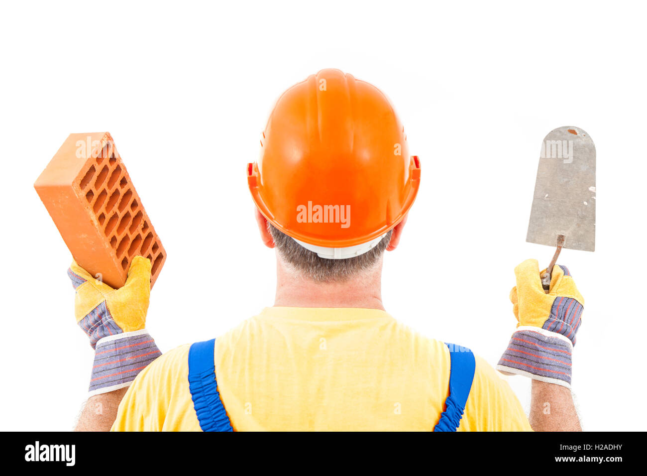 Construction Worker with hard hat holding gants truelle et brique dans ses mains isolé sur fond blanc. Banque D'Images