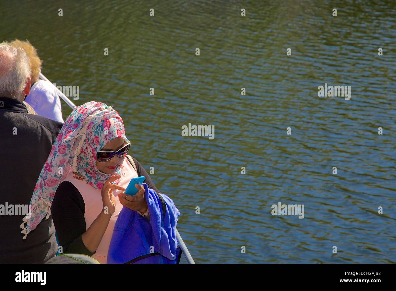 L'textng femme musulmane sur son téléphone portable à bord d'Ullswater Steamers recevez. Ullswater, Penrith, le Parc National de Lake District. Banque D'Images