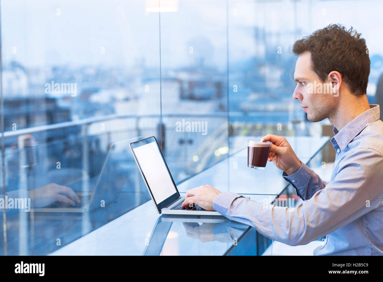 Jeune businessman reading e-mails sur l'ordinateur portable dans un café moderne Banque D'Images