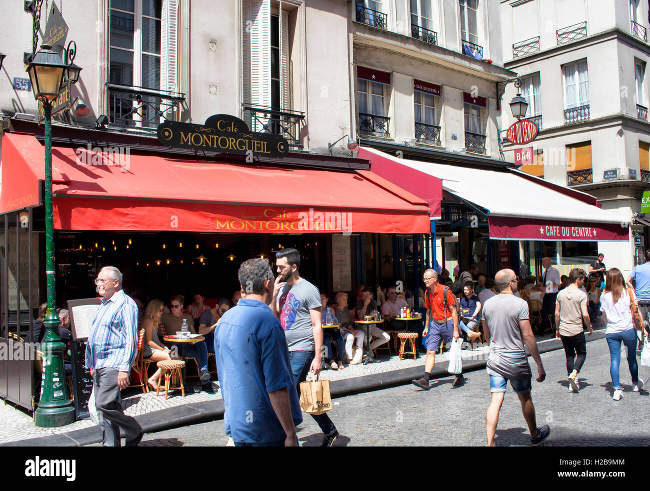 Les gens passe par un café sur la rue Montorgueil. Les gens ont le déjeuner/brunch au café et profiter du beau temps. Banque D'Images