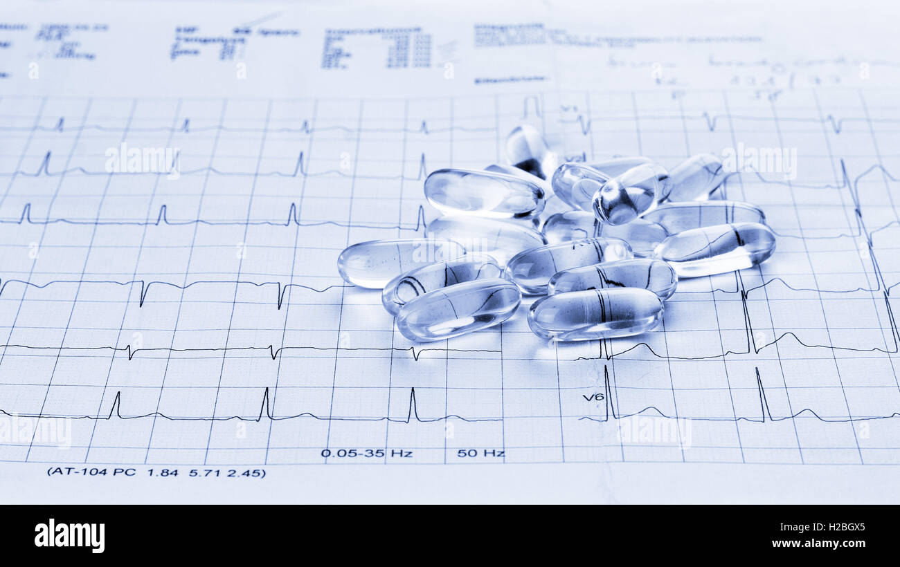 Ton bleu photo d'Omega 3 capsules de gel sur un électrocardiographe résultat de l'essai papier fond Banque D'Images