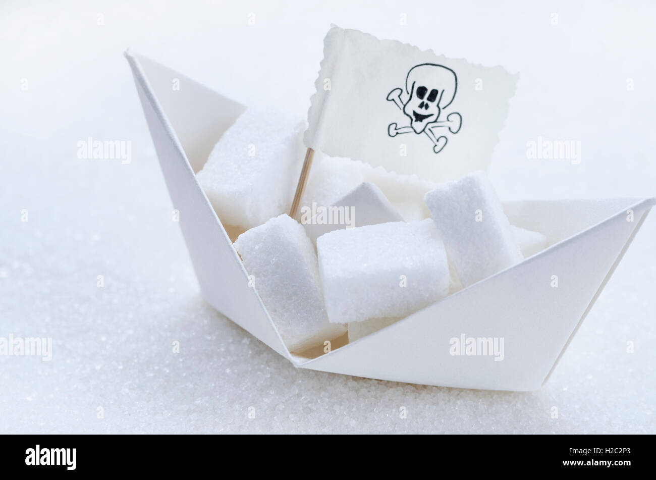 Cubes de sucre blanc dans un bateau en papier. Conceptual image concernent les enfants l'obésité et la nocivité de l'augmentation de la consommation de sucre Banque D'Images