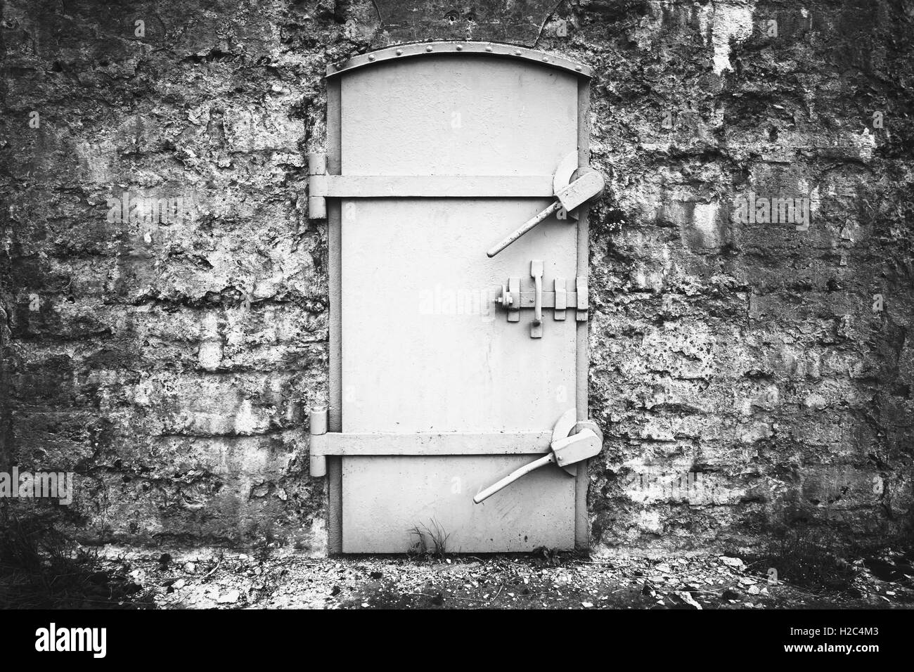 Porte métallique verrouillée dans le vieux mur de fortification, noir et wite texture contexte Banque D'Images