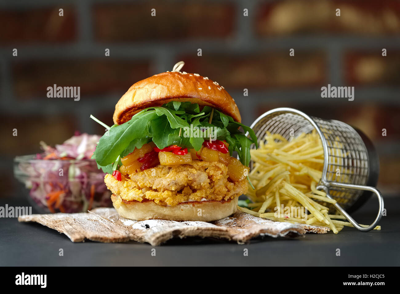 Sur les plaques en bois Chickenburger avec fromage, bacon, tomates, salade verte et rouge et frites. Banque D'Images