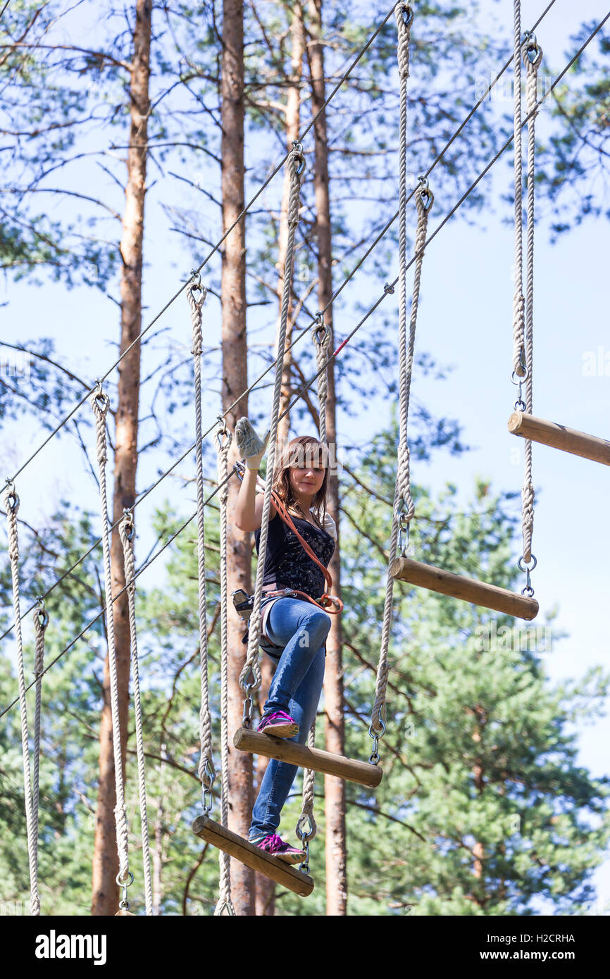 Jeune femme courageuse de l'escalade dans un parc aventure Banque D'Images