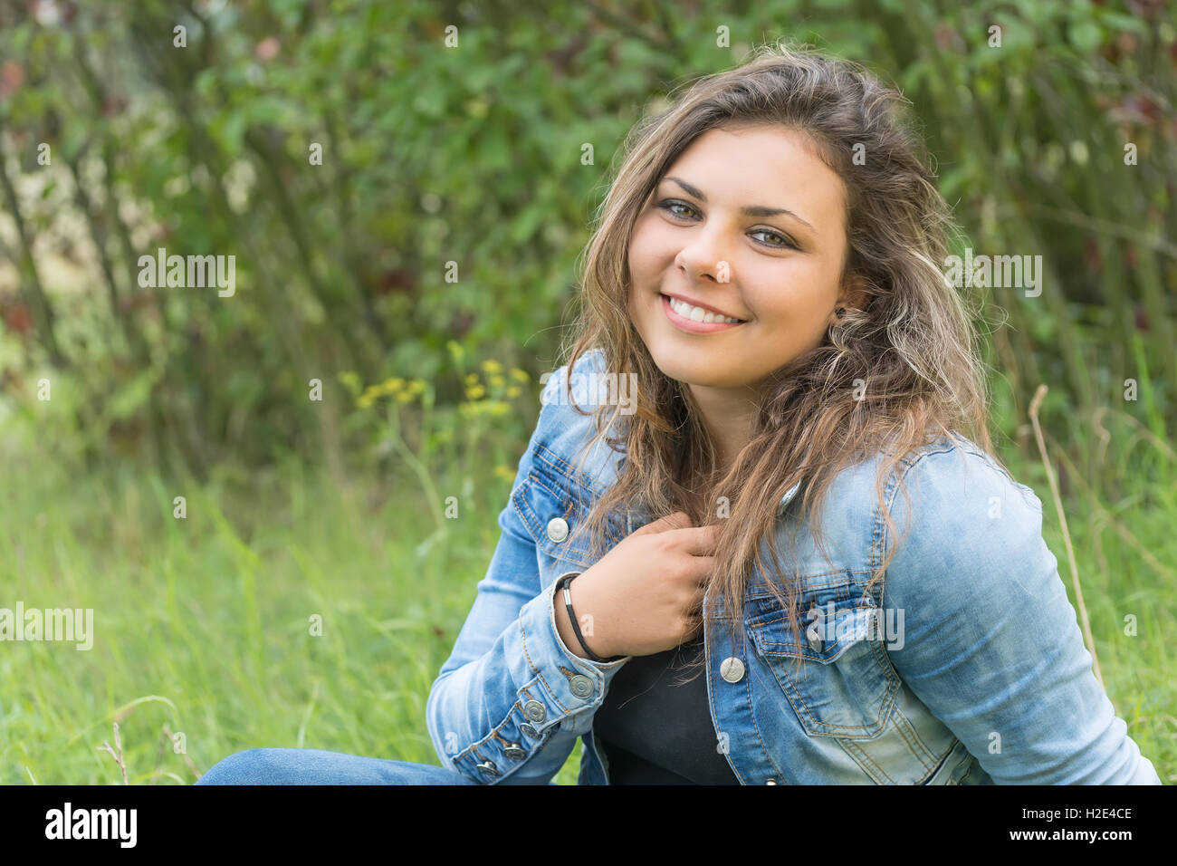 Portrait of laughing tête inclinée en arrière teenage girl sitting outdoors. Jeune fille est à la recherche de l'appareil photo. Banque D'Images