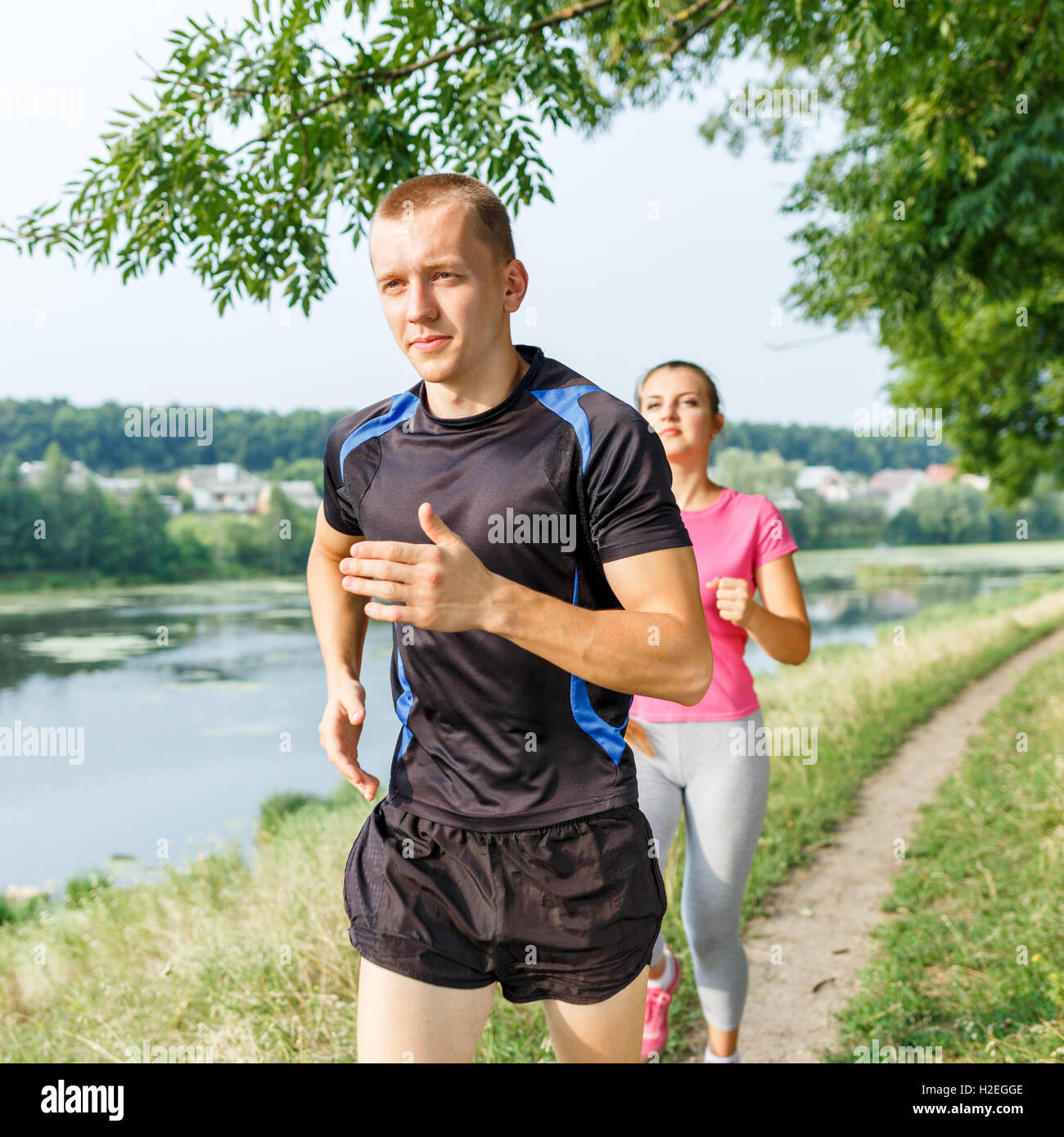 Les jeunes gens d'athlétisme en plein air jogging près de l'étang. L'homme et de la femme de faire exécuter l'exercice dans le parc Banque D'Images