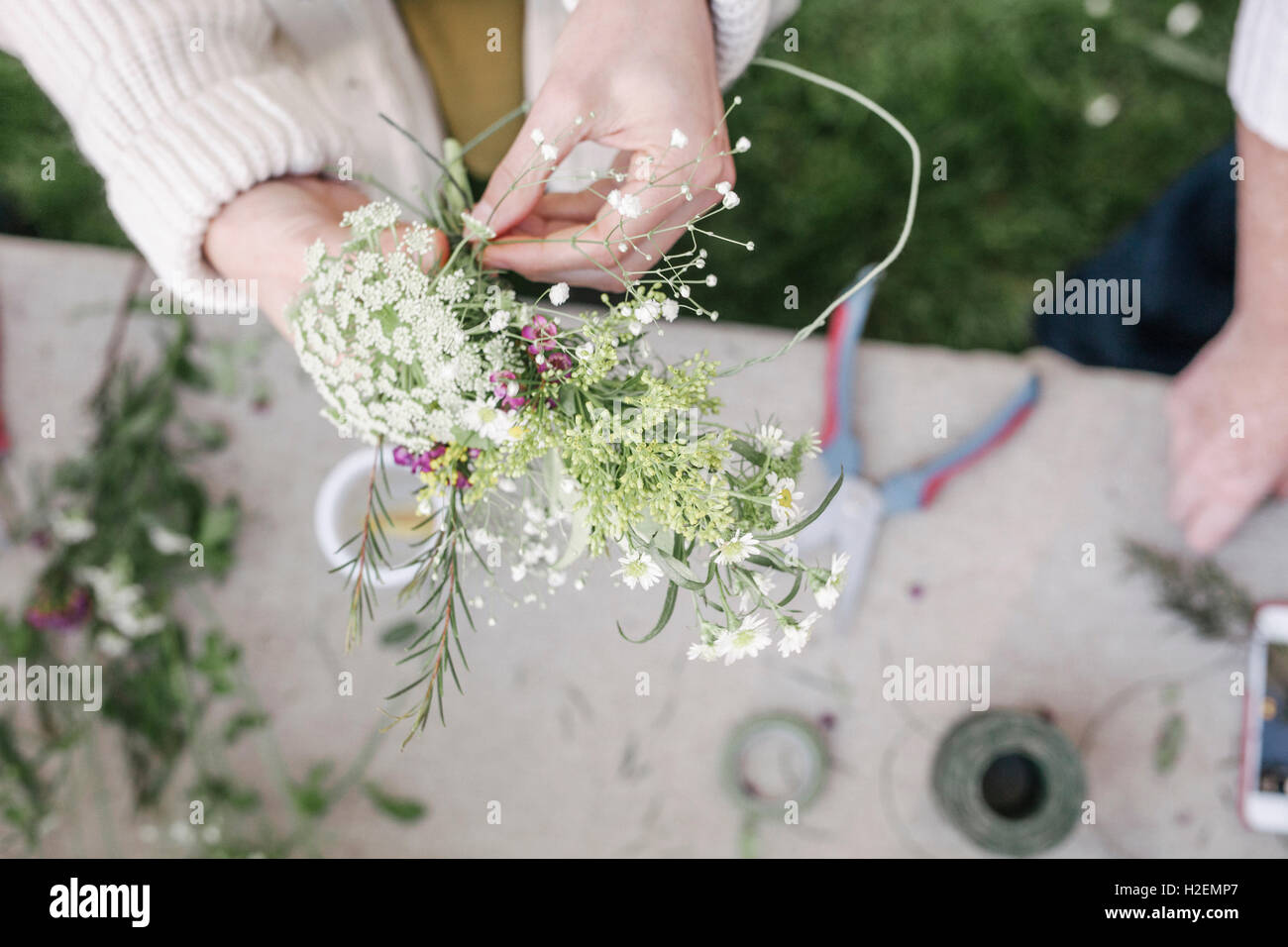 Portrait d'une femme, debout dans un jardin, faire une couronne de fleurs. Banque D'Images