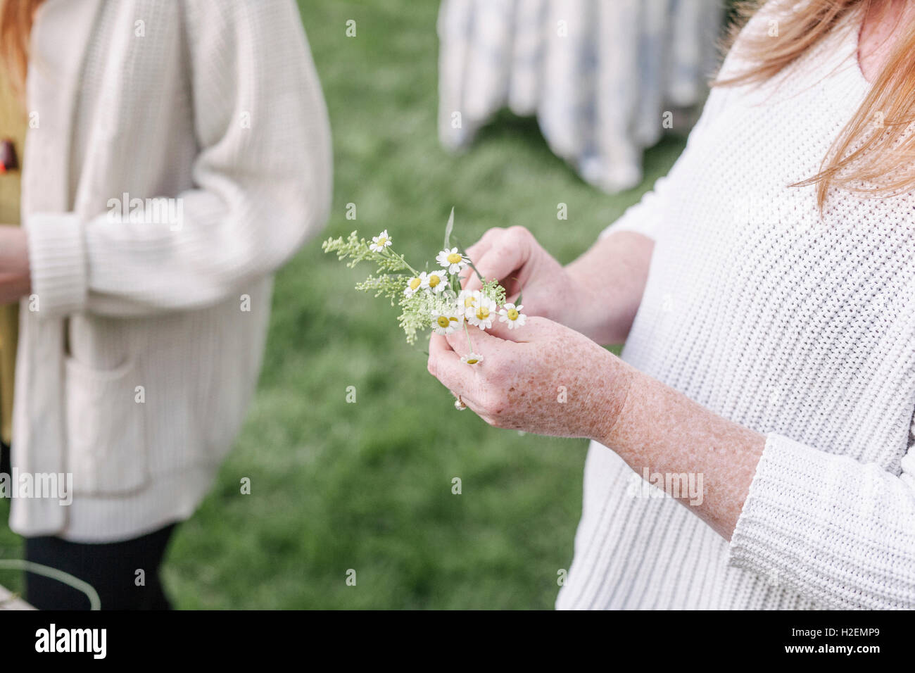 Portrait d'une femme, debout dans un jardin, faire une couronne de fleurs. Banque D'Images