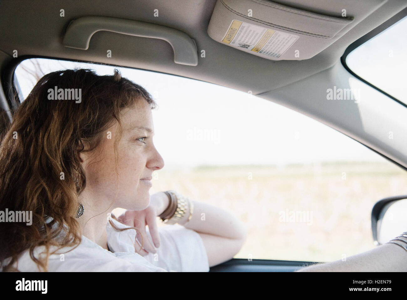 Femme dans une voiture sur un voyage sur la route, dans le siège conducteur, le coude sur la porte. Banque D'Images