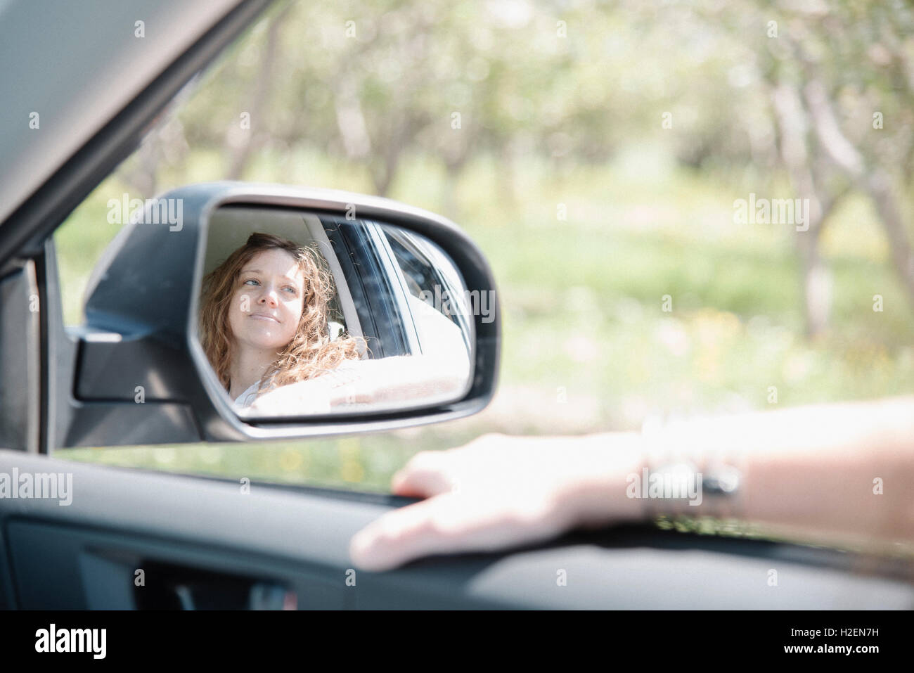 Femme dans une voiture sur un voyage sur la route, à la fenêtre de réflexion, vu dans le rétroviseur latéral. Banque D'Images