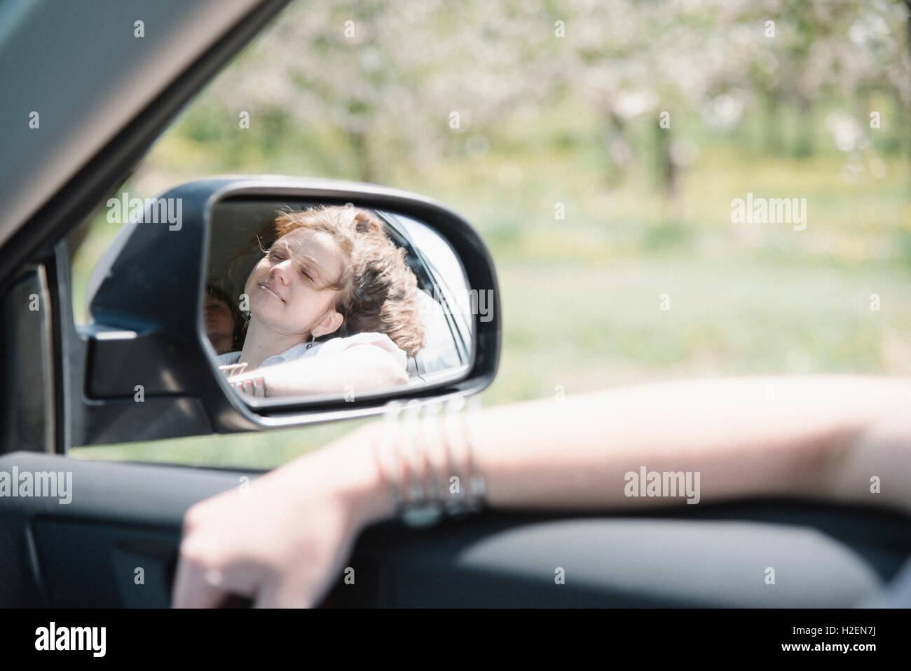 Femme dans une voiture sur un voyage sur la route, à la fenêtre de sortie, reflet dans le rétroviseur latéral. Banque D'Images