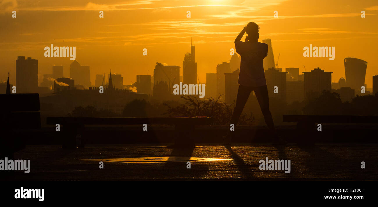 Primrose Hill, Londres, le 28 octobre 2016. Météo France : un matin tôt jogger sur Primrose Hill prend une photo de la magnifique lever de soleil sur les gratte-ciel de Londres. Crédit : Paul Davey/Alamy Live News Banque D'Images