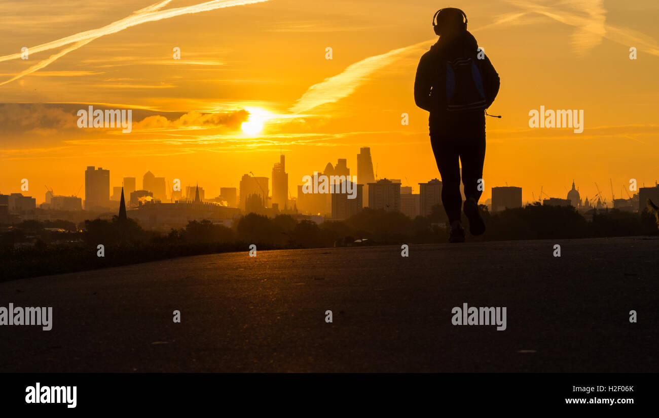 Primrose Hill, Londres, le 28 octobre 2016. Météo France : un jogger sur Primrose Hill est jeté dans la ville contre la silhouette des gratte-ciel comme le soleil se lève sur Londres. Crédit : Paul Davey/Alamy Live News Banque D'Images