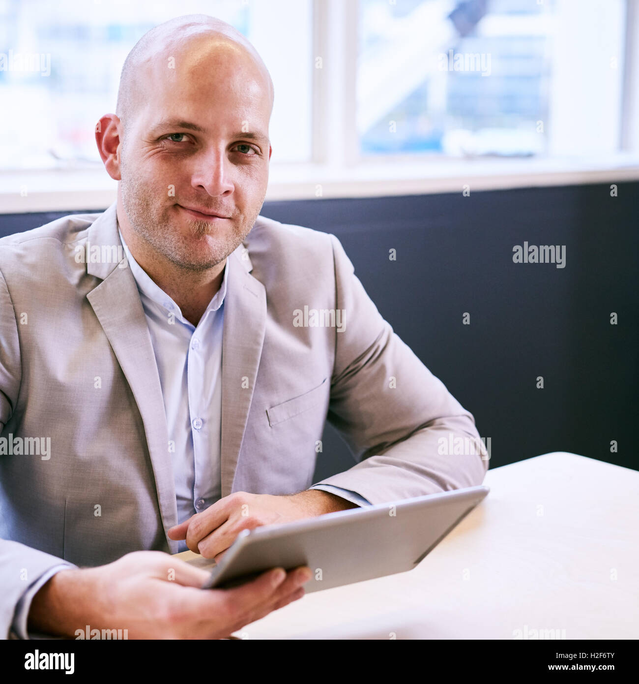 Happy business man holding tablet while looking at camera Banque D'Images