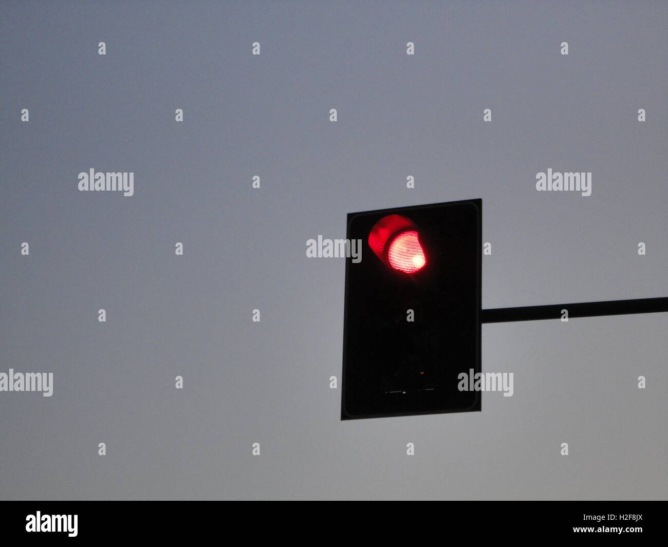 Le feu rouge au crépuscule contre un ciel bleu clair, Milan Banque D'Images