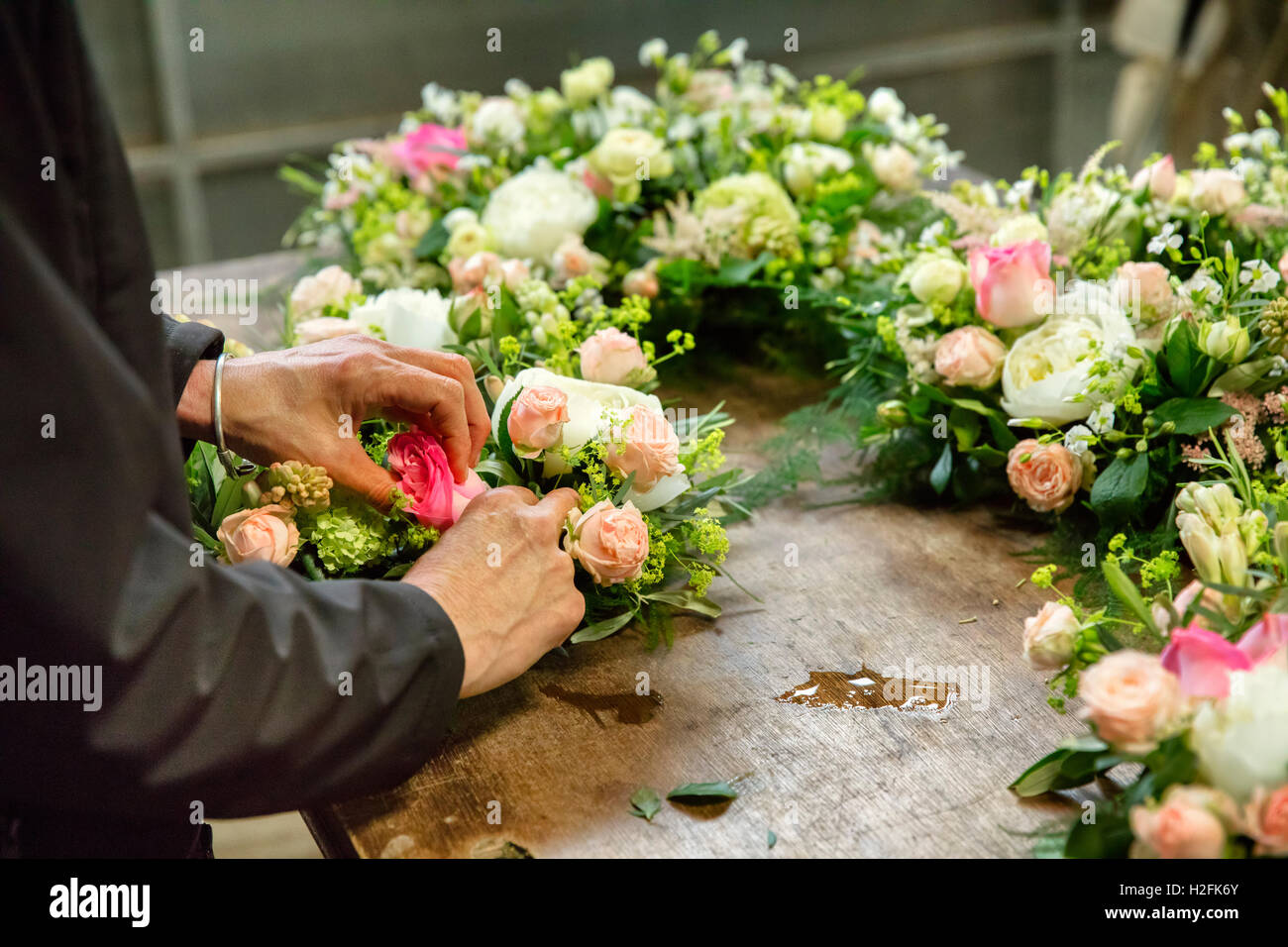 L'arrangement floral commercial. Un fleuriste, une femme travaillant sur une décoration florale à un établi. Banque D'Images