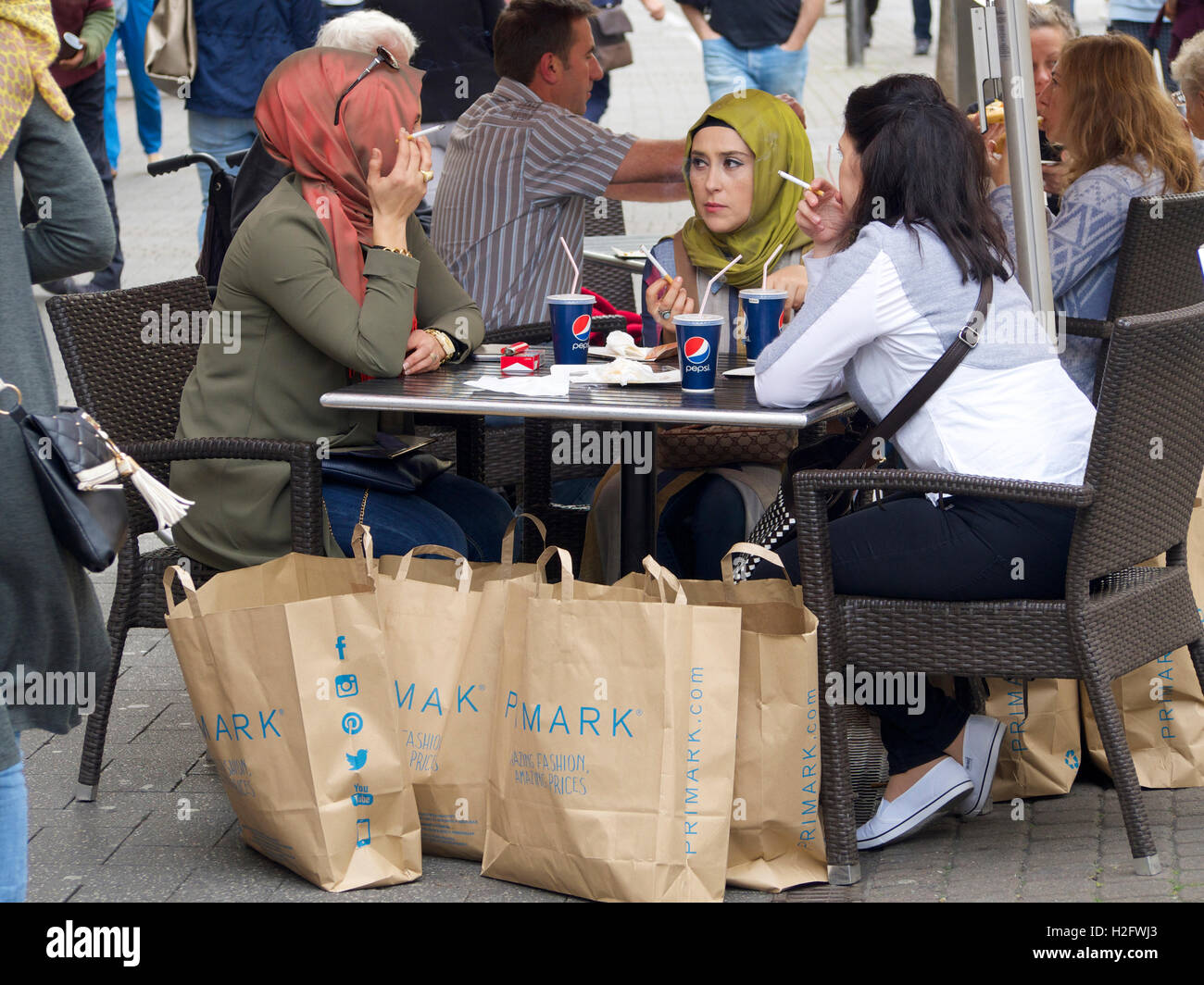 Les amis musulmans, fumeurs et haveing un Pepsi, qui ont fait du shopping à Primark à Cologne, Allemagne Banque D'Images