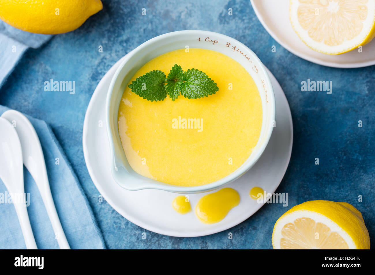 Le lait caillé de citron dans un bol en céramique avec des citrons frais sur une serviette bleu arrière-plan. Vue d'en haut. Selective focus Banque D'Images